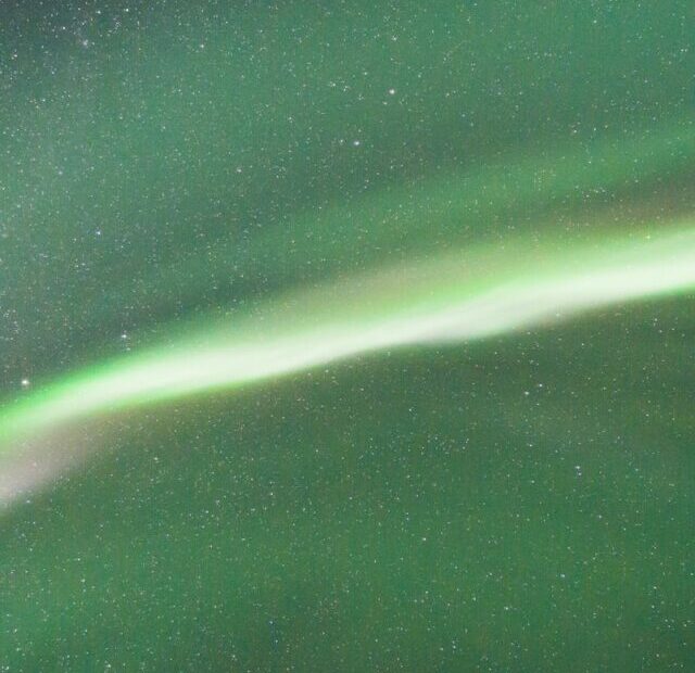 a green and white aurora bore in the night sky