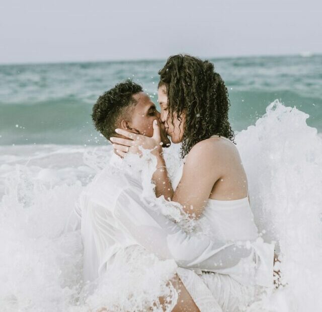 couple kissing on beach during daytime