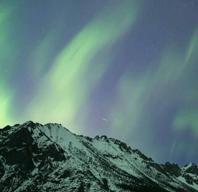 a mountain covered in snow under a green and purple sky