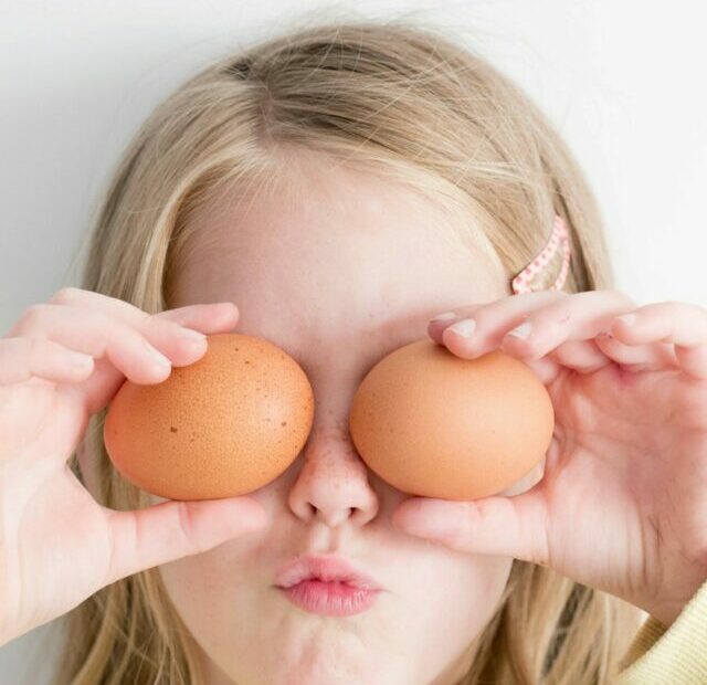 girl holding two eggs while putting it on her eyes