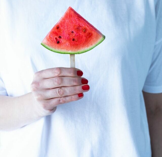 person in white crew neck t-shirt holding watermelon